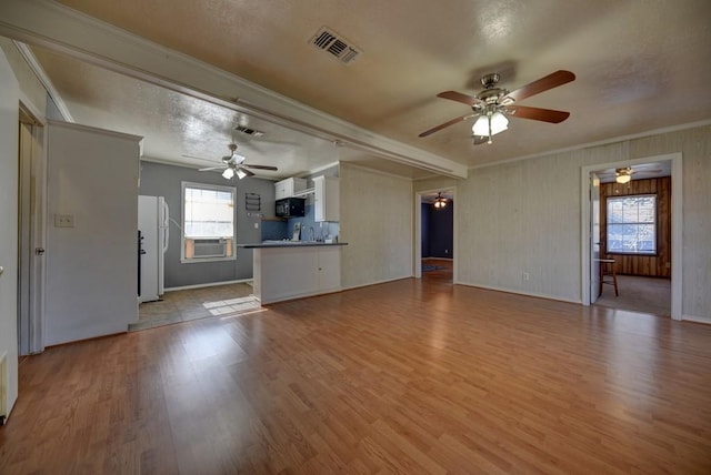 unfurnished living room featuring sink, cooling unit, ornamental molding, and light wood-type flooring