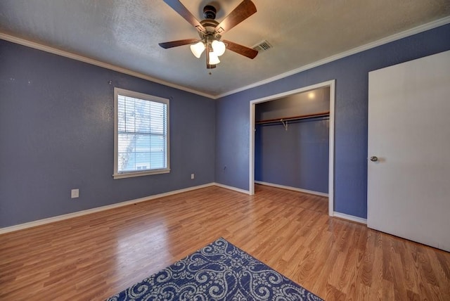 unfurnished bedroom with ceiling fan, a closet, ornamental molding, and light wood-type flooring