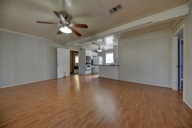 unfurnished living room featuring light hardwood / wood-style floors, wood walls, and crown molding