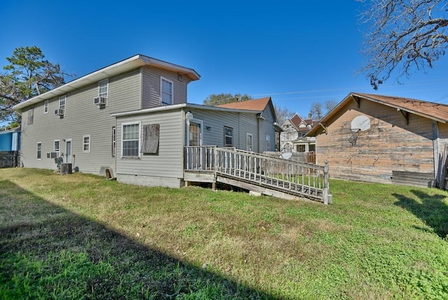 rear view of property with a deck, cooling unit, and a yard