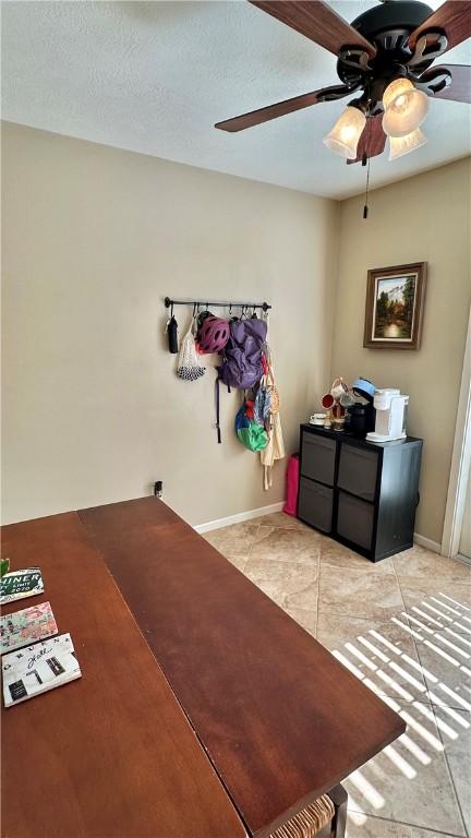 interior space with light tile patterned floors, baseboards, a textured ceiling, and a ceiling fan