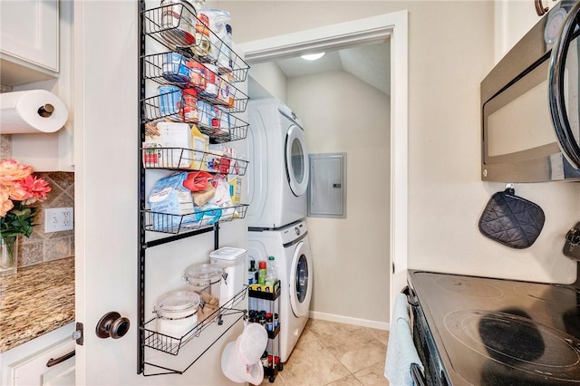 laundry area featuring baseboards, stacked washer and dryer, electric panel, laundry area, and light tile patterned flooring