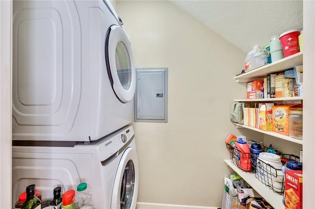 washroom featuring laundry area, electric panel, stacked washer and clothes dryer, and a textured ceiling