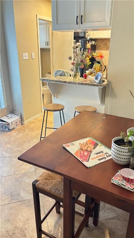 dining room with baseboards and light tile patterned flooring