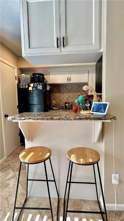 bar featuring tasteful backsplash and light tile patterned floors