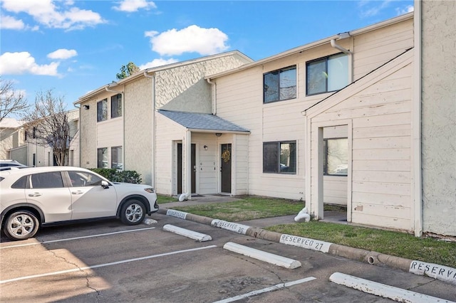 townhome / multi-family property with uncovered parking and roof with shingles