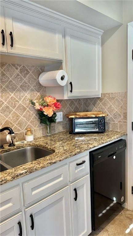 kitchen with a sink, tasteful backsplash, black dishwasher, and white cabinetry