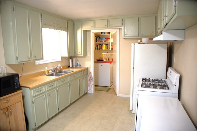 kitchen featuring fridge, independent washer and dryer, sink, and white range with gas stovetop