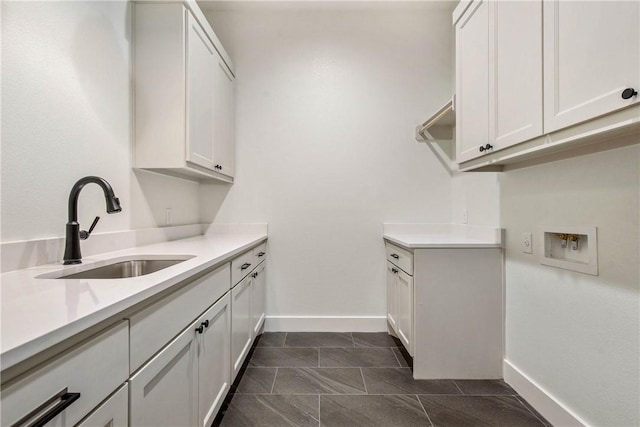 laundry room with cabinet space, hookup for a washing machine, baseboards, and a sink