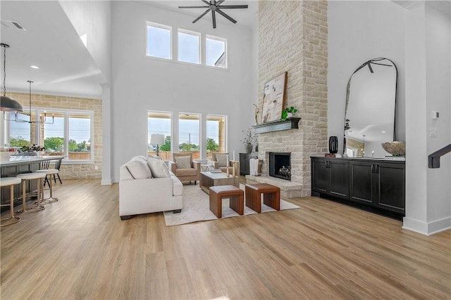 living room with a high ceiling, a healthy amount of sunlight, light wood-style floors, and a fireplace