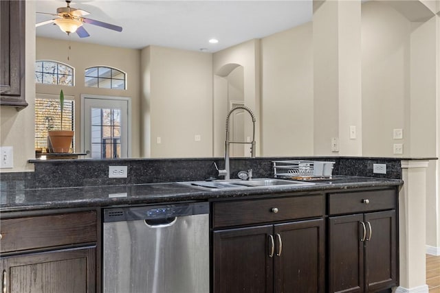 kitchen with stainless steel dishwasher, ceiling fan, dark stone counters, and sink