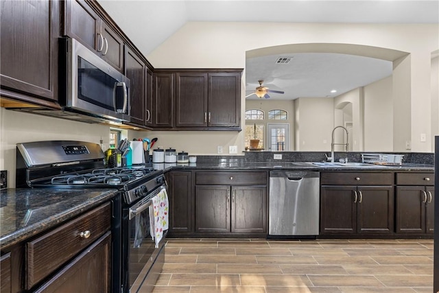 kitchen with dark stone counters, sink, ceiling fan, appliances with stainless steel finishes, and dark brown cabinets