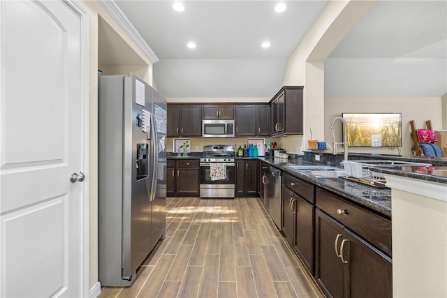 kitchen with sink, stainless steel appliances, dark stone countertops, dark brown cabinets, and ornamental molding