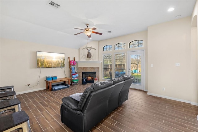 living room with a tile fireplace, ceiling fan, and lofted ceiling