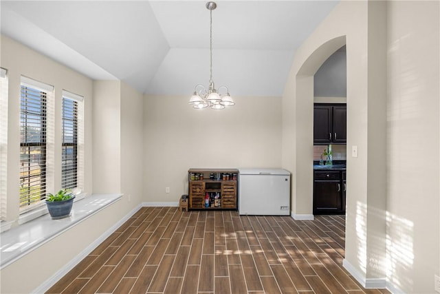 unfurnished dining area with a notable chandelier and vaulted ceiling