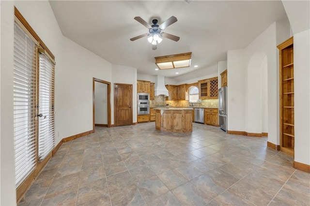 kitchen with backsplash, a center island, appliances with stainless steel finishes, baseboards, and custom exhaust hood