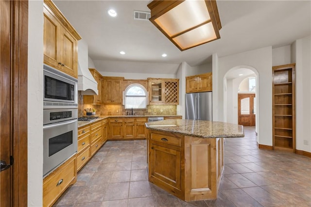 kitchen featuring visible vents, a sink, tasteful backsplash, arched walkways, and appliances with stainless steel finishes