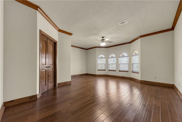 empty room with visible vents, crown molding, baseboards, ceiling fan, and dark wood-style flooring