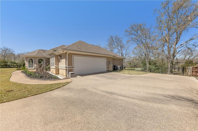 view of home's exterior featuring fence, roof with shingles, stucco siding, a garage, and driveway