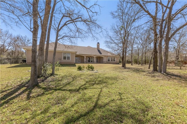 view of front of property featuring a front lawn, fence, a chimney, and stucco siding