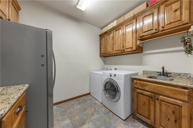 clothes washing area with washer and clothes dryer, cabinet space, baseboards, and a sink