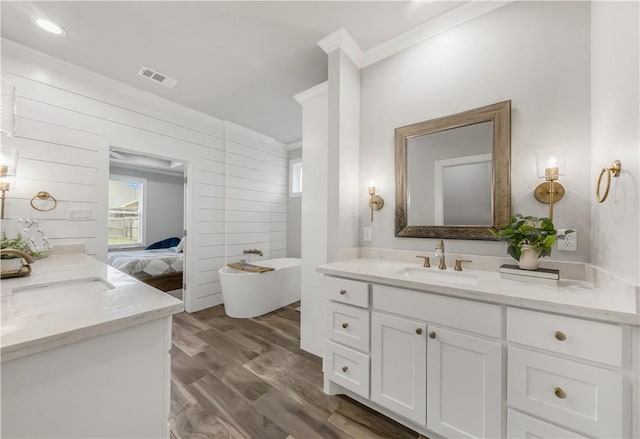 4813 Coopers Hawk Dr, College Station, TX 77845 - full bathroom featuring ornamental molding, two vanities, a freestanding bath, and wood finished floors