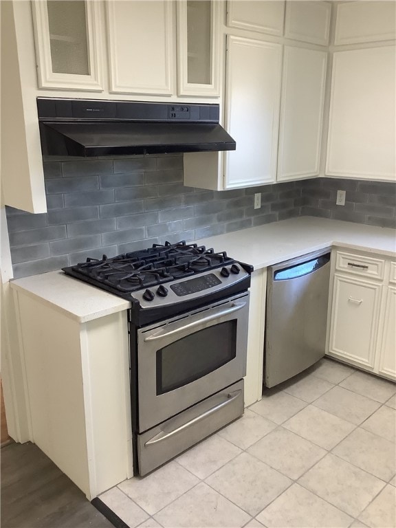 kitchen with tasteful backsplash, white cabinetry, light tile patterned floors, and stainless steel appliances