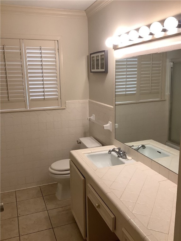 bathroom with tile patterned flooring, crown molding, toilet, vanity, and tile walls