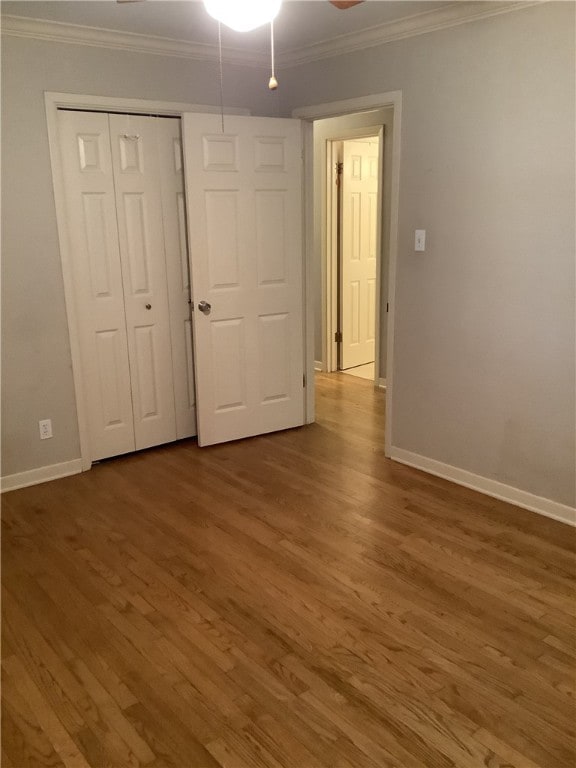 unfurnished bedroom with dark hardwood / wood-style floors, crown molding, and a closet