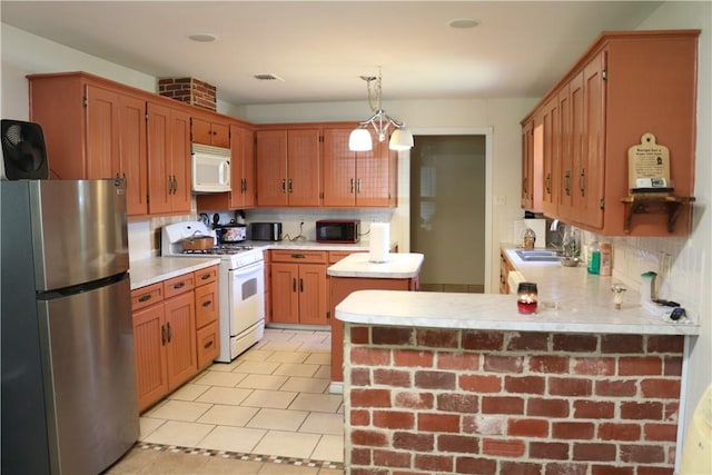 106 N Minden St, Madisonville, TX 77864 - kitchen featuring white appliances, light countertops, a peninsula, hanging light fixtures, and decorative backsplash