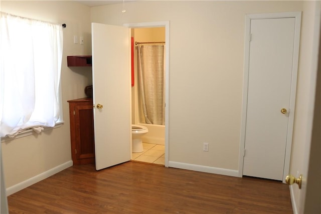 106 N Minden St, Madisonville, TX 77864 - unfurnished bedroom with multiple windows, wood finished floors, and ensuite bathroom