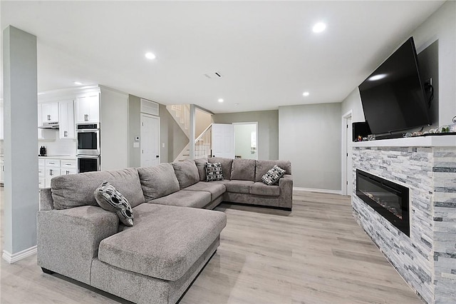 living room featuring light hardwood / wood-style flooring and a stone fireplace