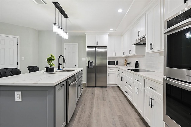 kitchen with a kitchen breakfast bar, sink, an island with sink, white cabinetry, and stainless steel appliances