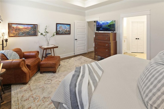 bedroom with ornamental molding, ensuite bathroom, and wood-type flooring