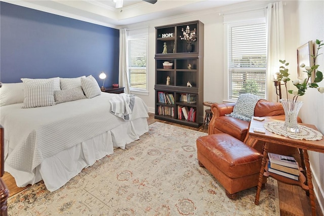 bedroom featuring multiple windows, hardwood / wood-style flooring, ornamental molding, and ceiling fan