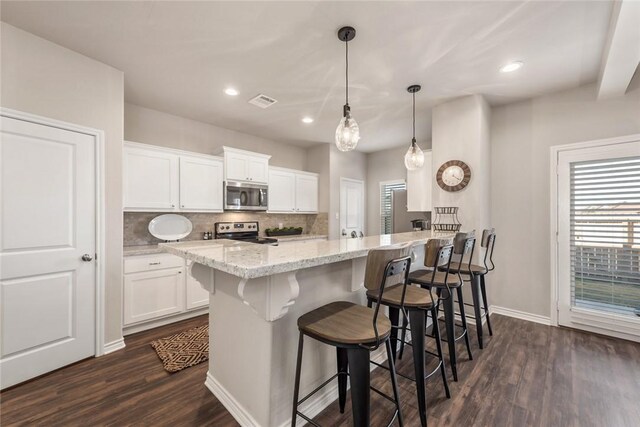 kitchen featuring white cabinetry, stainless steel appliances, light stone countertops, and pendant lighting