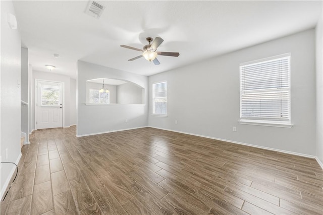 empty room with baseboards, wood finished floors, visible vents, and a ceiling fan