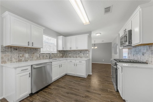 kitchen featuring sink, dark hardwood / wood-style flooring, decorative backsplash, white cabinets, and appliances with stainless steel finishes