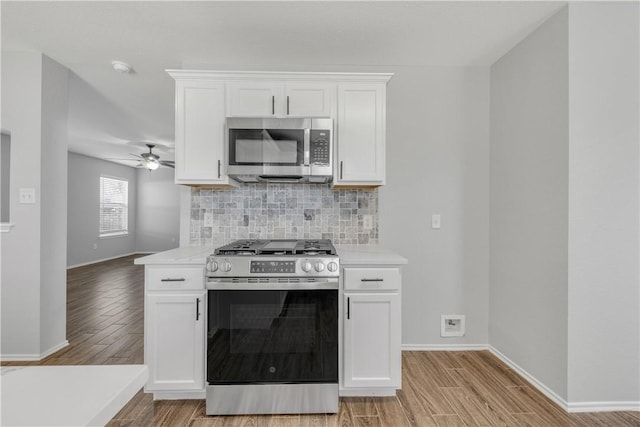 kitchen featuring appliances with stainless steel finishes, light wood-type flooring, white cabinetry, and ceiling fan