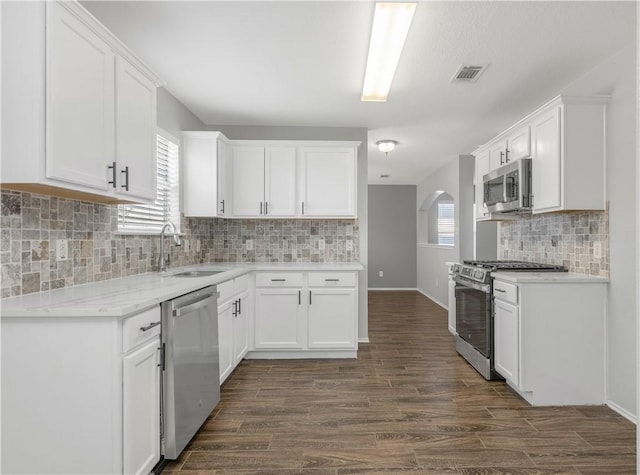 kitchen with visible vents, white cabinets, dark wood-type flooring, stainless steel appliances, and a sink