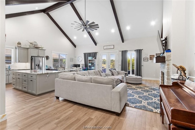 living room with light wood-type flooring, high vaulted ceiling, plenty of natural light, and ceiling fan