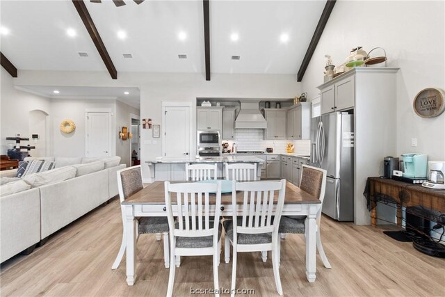 dining area with vaulted ceiling with beams and light hardwood / wood-style flooring