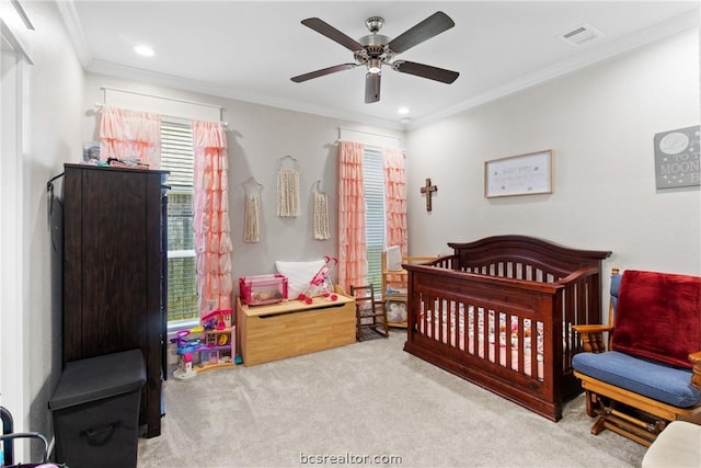 carpeted bedroom with a crib, ceiling fan, and ornamental molding