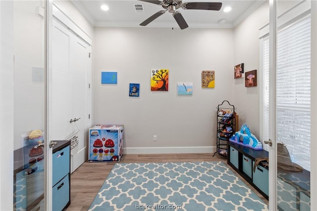 playroom with ceiling fan, wood-type flooring, and crown molding