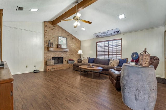 living room with vaulted ceiling with beams, ceiling fan, dark hardwood / wood-style floors, and a brick fireplace