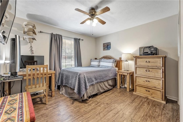 bedroom with ceiling fan, a textured ceiling, and light wood-type flooring