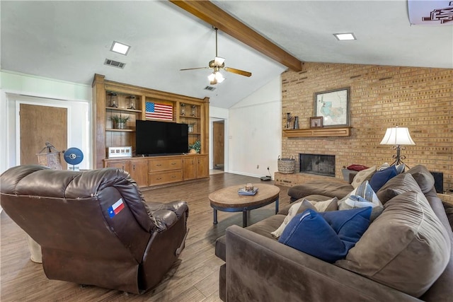 living room featuring hardwood / wood-style flooring, vaulted ceiling with beams, ceiling fan, a fireplace, and brick wall