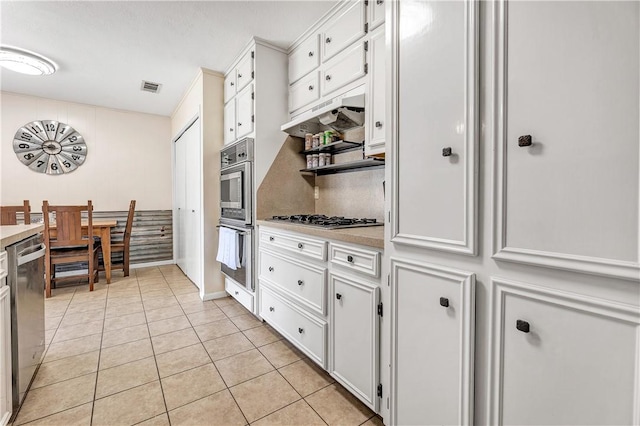 kitchen featuring appliances with stainless steel finishes, light tile patterned floors, and white cabinetry