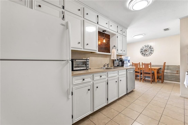 kitchen with stainless steel dishwasher, white fridge, white cabinetry, and light tile patterned floors