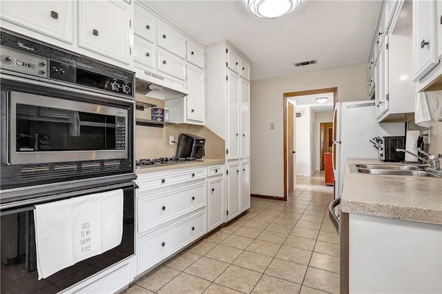 kitchen featuring tasteful backsplash, sink, light tile patterned floors, white cabinetry, and stainless steel gas stovetop